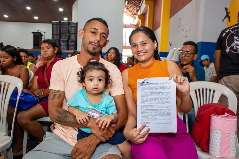 O casal Amanda Martins e Alex Uchoa, acompanhados da filha Ana Victoria, apresentam o documento da casa própria, que representa moradia com dignidade