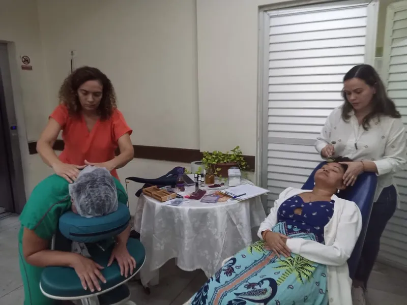 As servidoras Suelen do Nascimento (de verde) e Ana Carolina Mata recebem tratamento das terapeutas voluntárias do Consultório PICS na ação "Janeiro Branco - cuidado na mente, cuidando da vida".